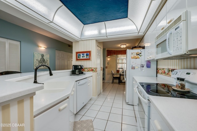 kitchen featuring light tile patterned flooring, sink, white cabinetry, a tray ceiling, and white appliances