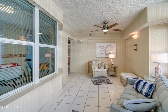 living room featuring light tile patterned floors, a textured ceiling, and ceiling fan