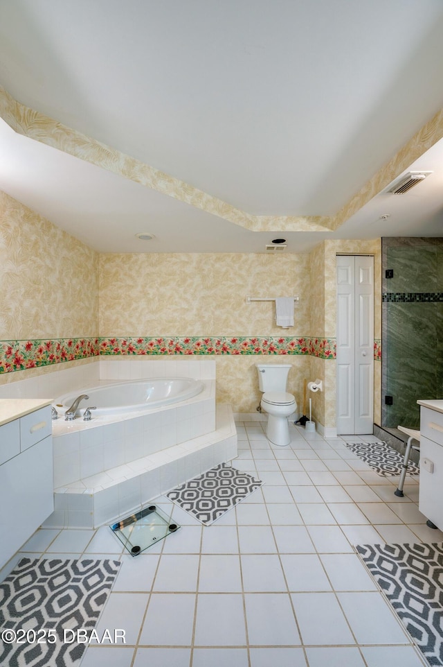 bathroom featuring tile patterned flooring, vanity, tiled tub, and toilet