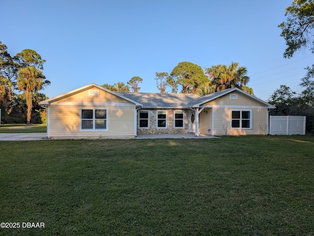 ranch-style home with stone siding, a front lawn, and fence