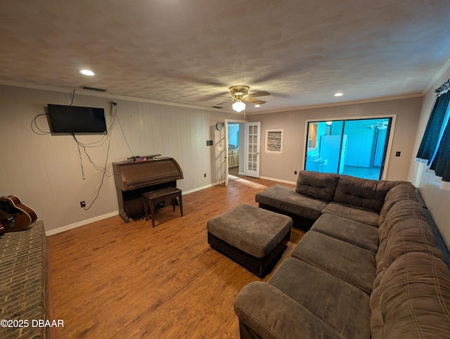 living area with crown molding, wood finished floors, baseboards, and ceiling fan