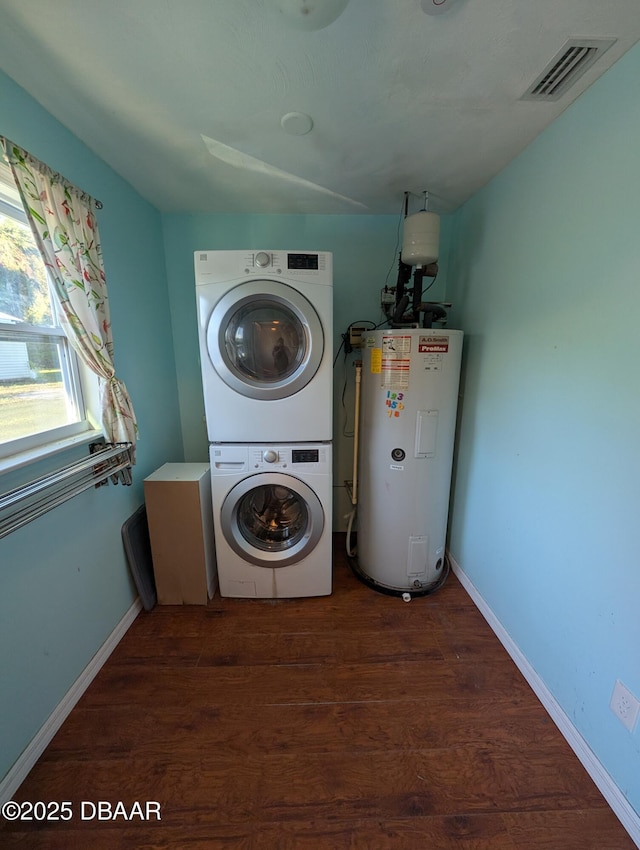 clothes washing area with visible vents, dark wood finished floors, water heater, stacked washer / drying machine, and laundry area
