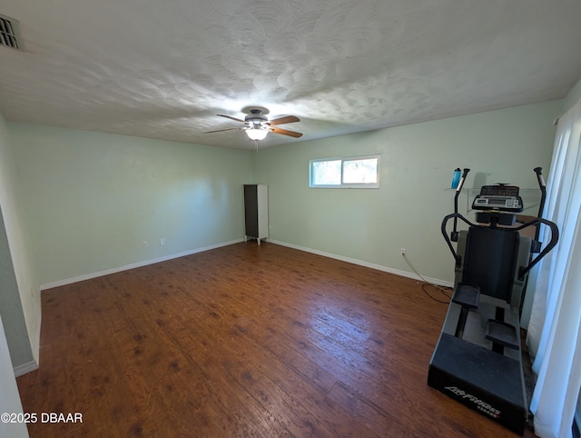 exercise room featuring a ceiling fan, visible vents, wood finished floors, baseboards, and a textured ceiling