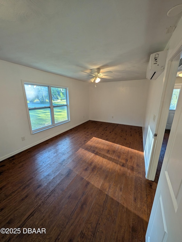 spare room with baseboards, a wall mounted AC, ceiling fan, and wood-type flooring