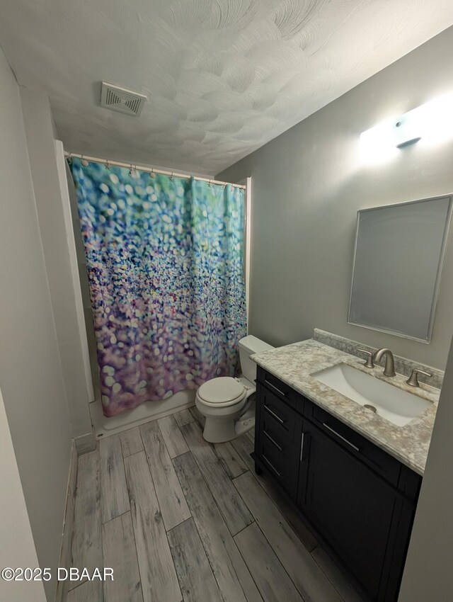 full bathroom with visible vents, toilet, vanity, and wood finished floors