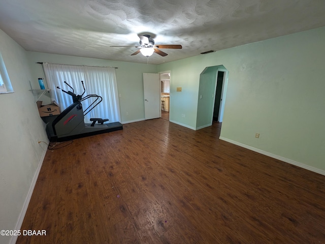 interior space featuring visible vents, a ceiling fan, wood finished floors, arched walkways, and baseboards