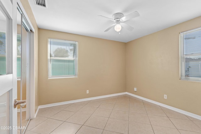 tiled empty room featuring ceiling fan and a healthy amount of sunlight