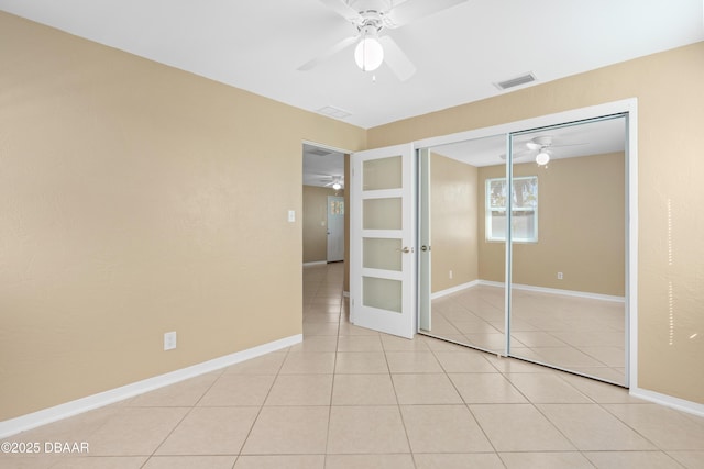 unfurnished bedroom with french doors, light tile patterned flooring, ceiling fan, and a closet