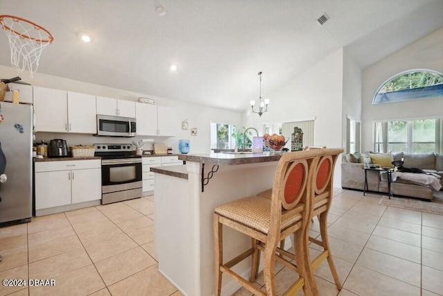 kitchen featuring stainless steel appliances, hanging light fixtures, an inviting chandelier, a breakfast bar, and white cabinets