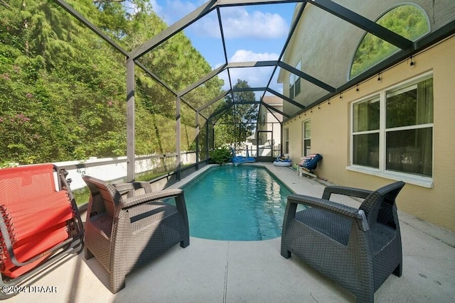 view of pool featuring glass enclosure and a patio area