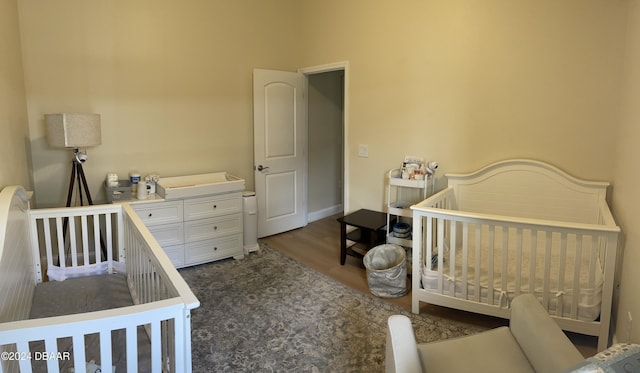 bedroom featuring a crib and dark wood-type flooring