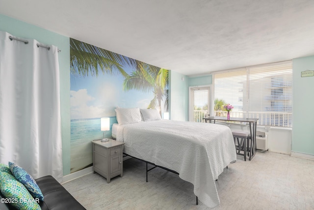bedroom featuring baseboards, a wall unit AC, and light wood-style flooring
