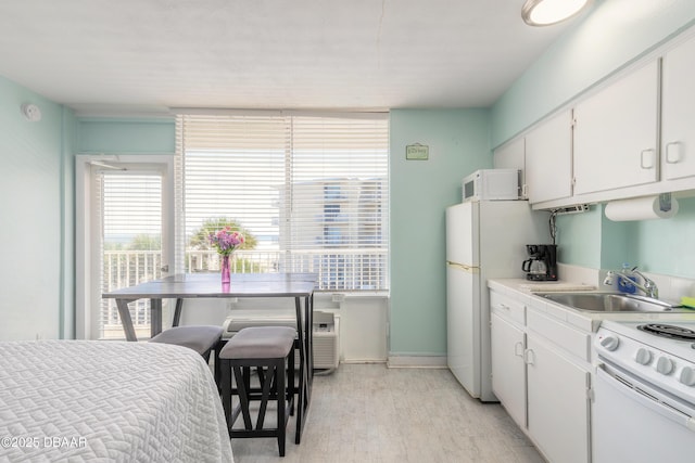 kitchen featuring a sink, plenty of natural light, white appliances, and white cabinetry
