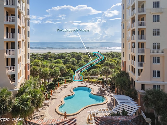 view of swimming pool with a water view and a beach view