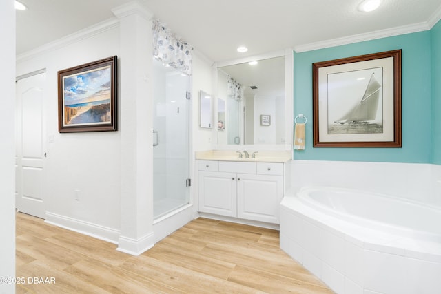 full bathroom featuring ornamental molding, a stall shower, wood finished floors, a bath, and vanity