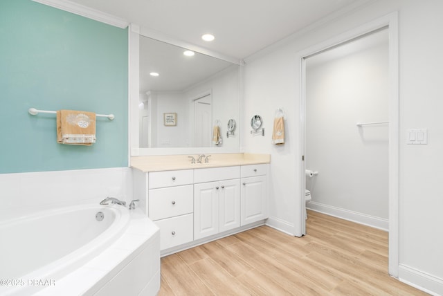 bathroom featuring toilet, wood finished floors, crown molding, a bath, and vanity