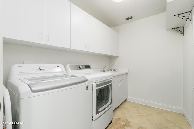 washroom featuring cabinets, separate washer and dryer, a textured ceiling, and light tile patterned floors