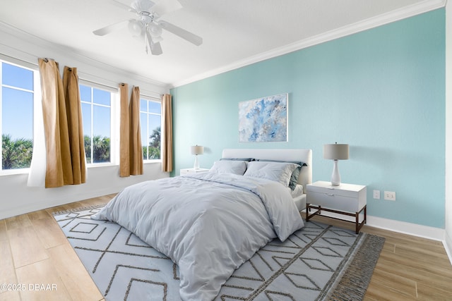 bedroom featuring a ceiling fan, crown molding, wood finished floors, and baseboards