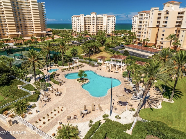 pool featuring a view of city, fence, a patio area, and a water view