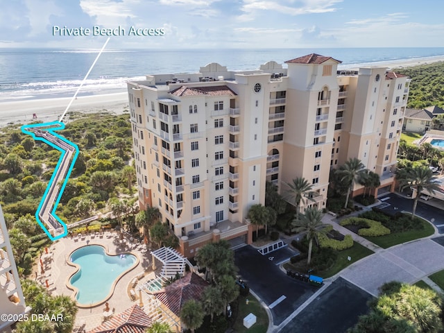 view of building exterior featuring a water view and a beach view