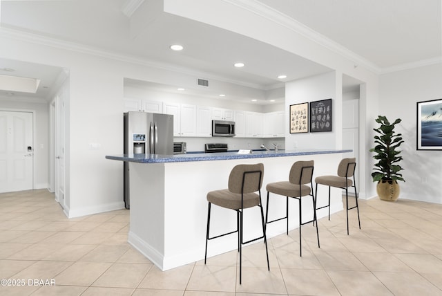 kitchen featuring visible vents, a breakfast bar, ornamental molding, appliances with stainless steel finishes, and light tile patterned flooring