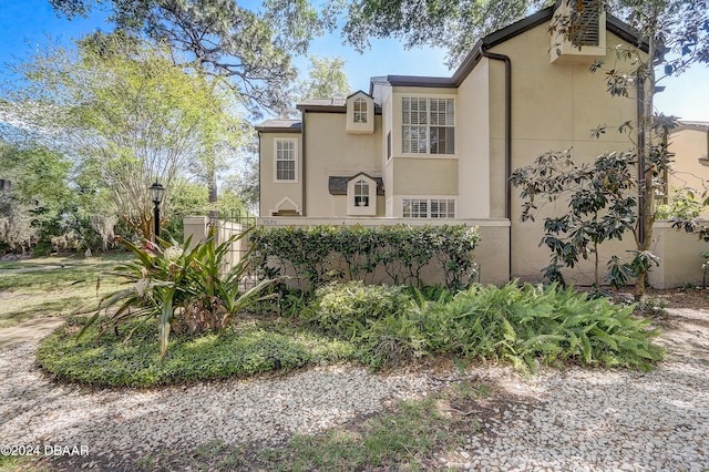 view of side of property with stucco siding and fence