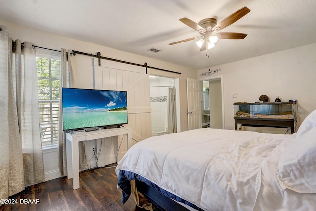 bedroom with visible vents, ceiling fan, a barn door, wood finished floors, and a textured ceiling