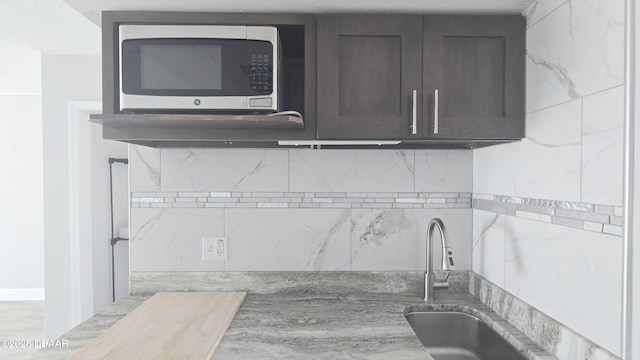 219 S Atlantic Ave Unit 120, Daytona Beach, FL 32118 - kitchen featuring tasteful backsplash, stainless steel microwave, a sink, and dark brown cabinetry