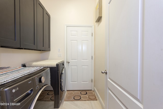 laundry area featuring washing machine and dryer, light tile patterned flooring, and cabinets