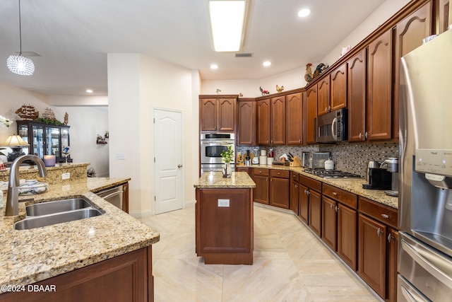 kitchen featuring pendant lighting, sink, light stone countertops, an island with sink, and stainless steel appliances