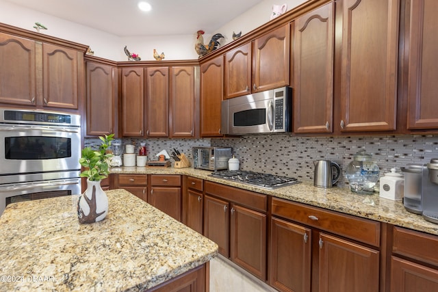 kitchen with light stone counters, stainless steel appliances, and tasteful backsplash