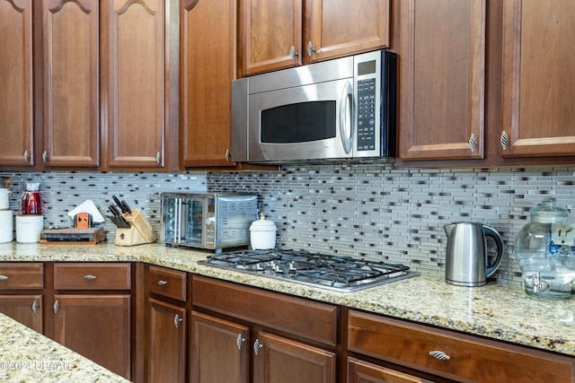 kitchen with decorative backsplash, appliances with stainless steel finishes, and light stone counters