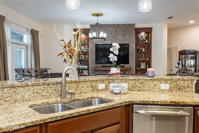 kitchen featuring dishwasher, light stone counters, sink, and decorative light fixtures