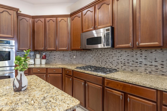 26 Ethel Ln, Palm Coast, FL 32164 - kitchen with brown cabinetry, light stone counters, stainless steel appliances, and decorative backsplash
