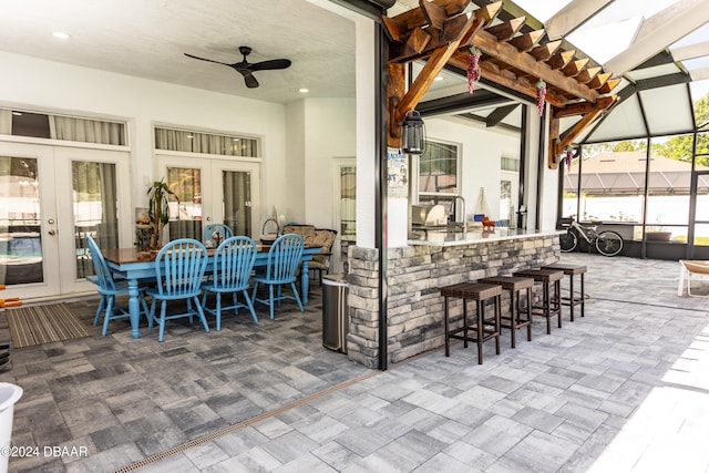 view of patio with ceiling fan, a bar, and french doors