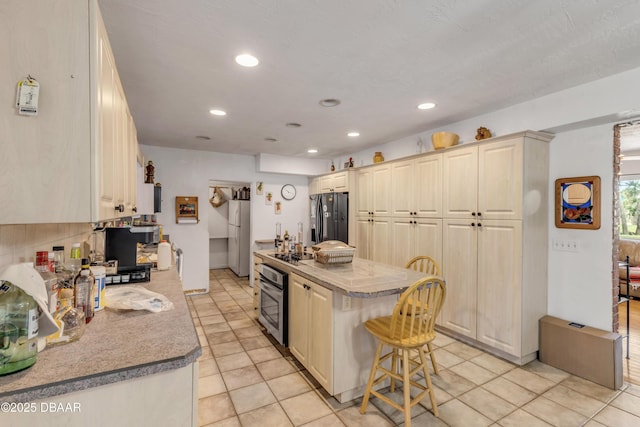 327 Due E St, New Smyrna Beach, FL 32169 - kitchen with black appliances, a kitchen island, recessed lighting, light tile patterned floors, and a breakfast bar