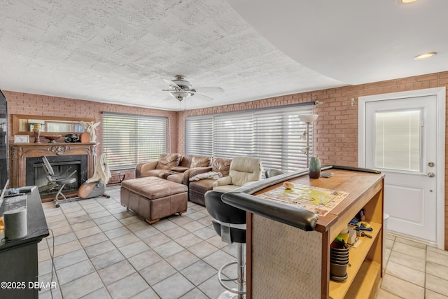 327 Due E St, New Smyrna Beach, FL 32169 - living area featuring light tile patterned flooring, brick wall, ceiling fan, and a fireplace with raised hearth