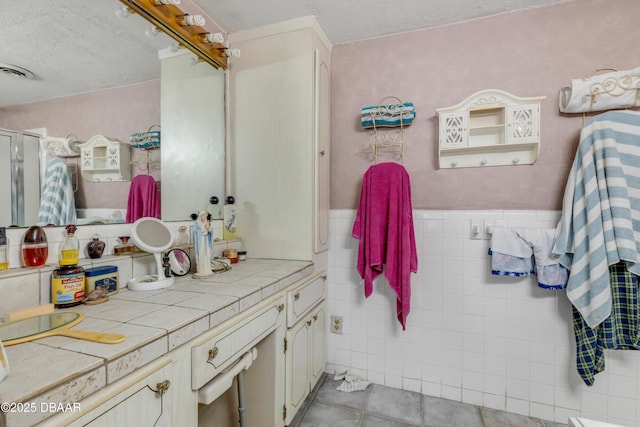 327 Due E St, New Smyrna Beach, FL 32169 - bathroom with vanity, an enclosed shower, tile patterned flooring, a textured ceiling, and tile walls