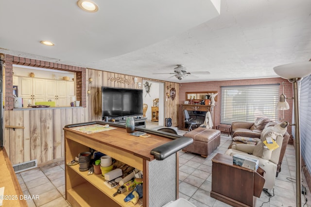 327 Due E St, New Smyrna Beach, FL 32169 - living room featuring wood walls, a ceiling fan, light tile patterned floors, and a wood stove