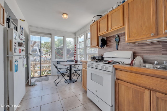 kitchen featuring white appliances, light tile patterned floors, sink, and tasteful backsplash