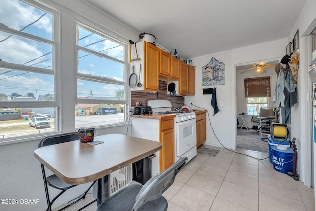 kitchen with ceiling fan, a healthy amount of sunlight, white gas stove, and light tile patterned floors