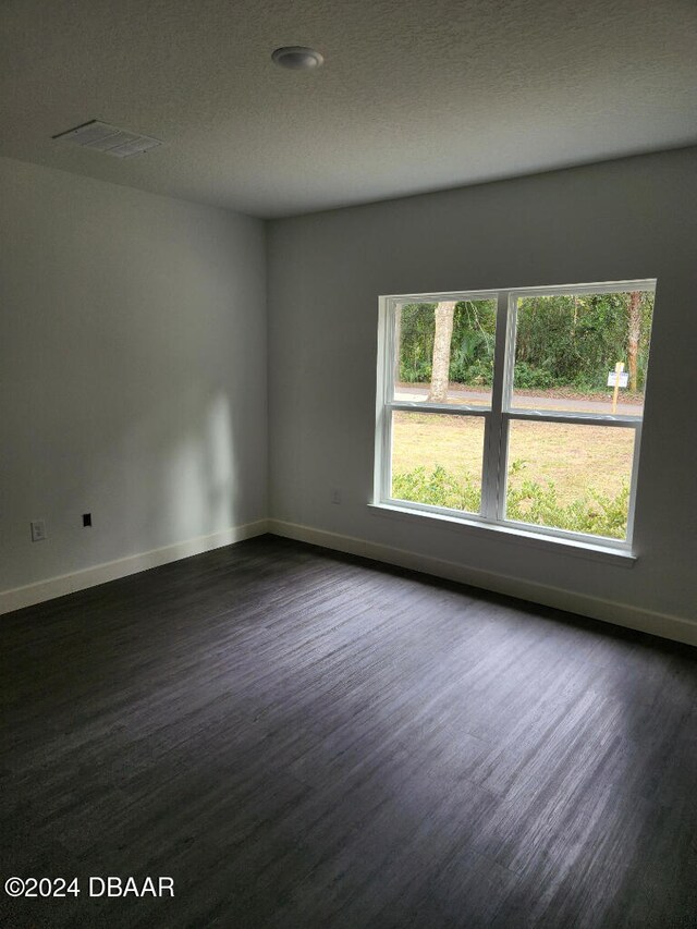 empty room with dark wood-type flooring and a textured ceiling