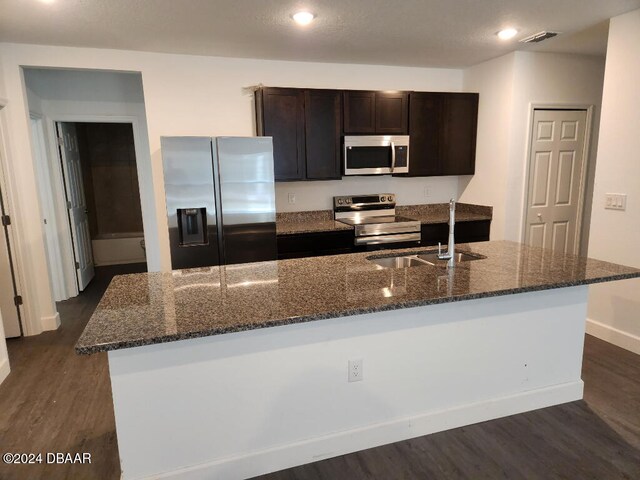 kitchen with a kitchen island with sink, dark hardwood / wood-style flooring, sink, and stainless steel appliances