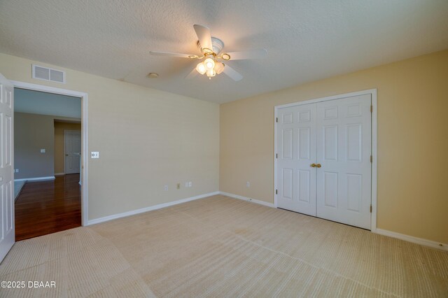 unfurnished bedroom featuring visible vents, baseboards, a closet, and light colored carpet