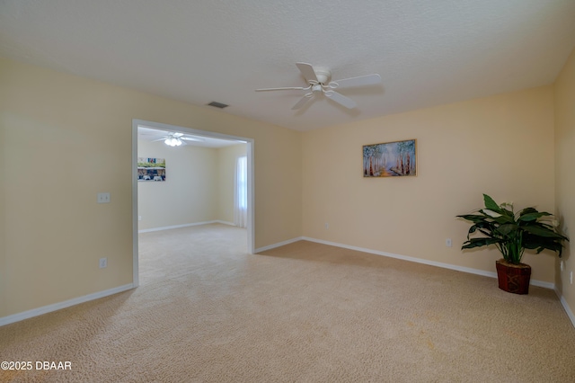 carpeted empty room with visible vents, a ceiling fan, and baseboards