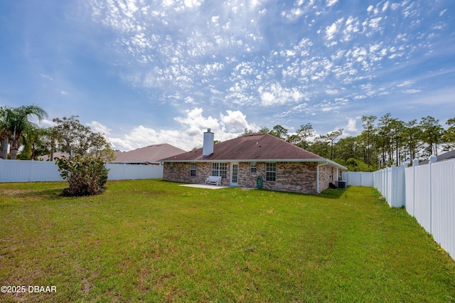 rear view of property featuring a lawn, a chimney, a patio area, and a fenced backyard