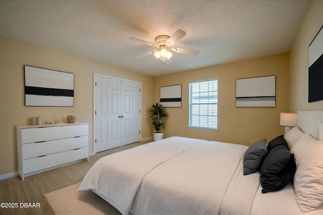bedroom featuring baseboards, a ceiling fan, light wood finished floors, and a closet