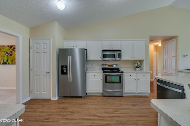 kitchen featuring white cabinetry, appliances with stainless steel finishes, and vaulted ceiling