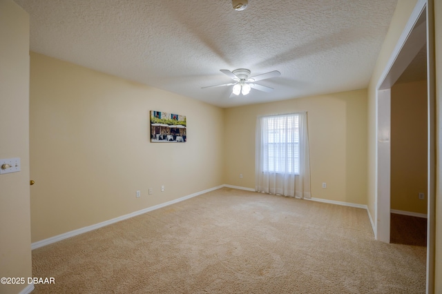 carpeted spare room featuring a textured ceiling, ceiling fan, and baseboards