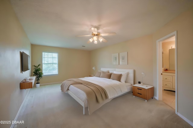 bedroom with baseboards, light carpet, and ensuite bathroom